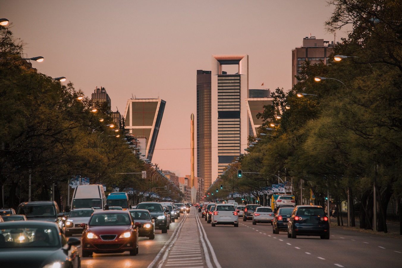 Coches circulando por el Paseo de la Castellana de Madrid con las cuatro torres de fondo