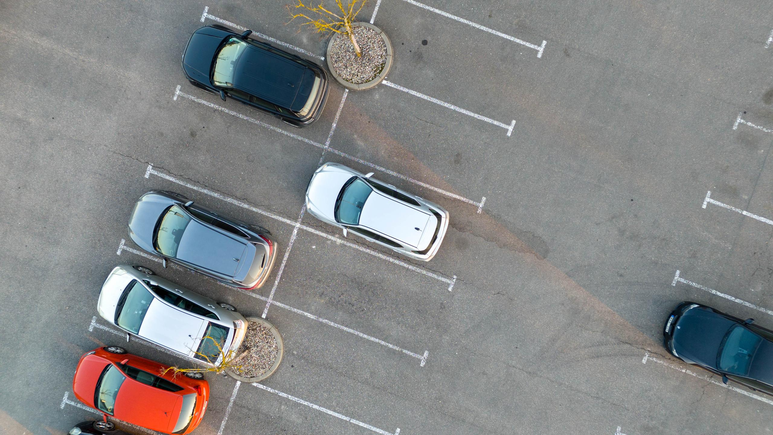 Vista aérea de un aparcamiento al aire libre con varios coches y muchas plazas libres